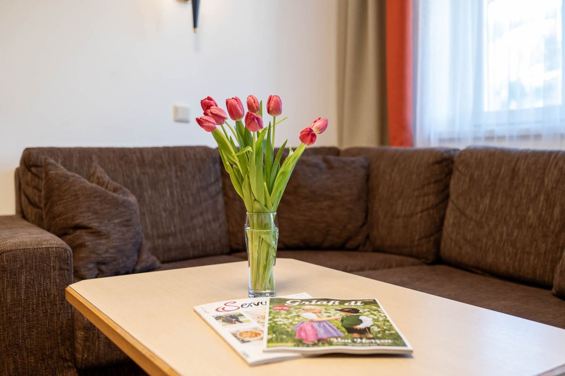 Gemütlicher Wohnbereich im Appartementhaus Grafenbergblick mit Sofa, Blumenstrauß und Zeitschriften