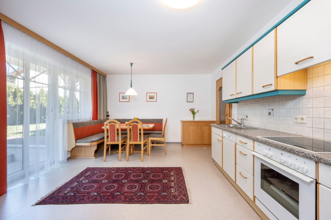 Helle Wohnküche im Appartement mit Essecke, kompletter Küchenausstattung und Zugang zur Terrasse