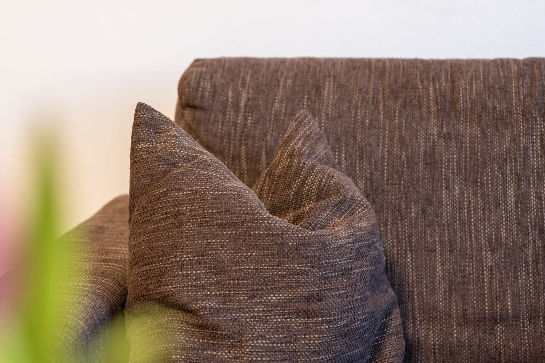 Detailaufnahme eines braunen Sofakissens im Wohnzimmer des Appartements