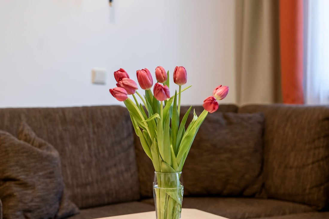 Vase mit Tulpen auf einem Couchtisch vor einem braunen Sofa im Wohnbereich